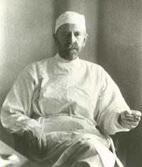 Black and white photo of Dr. Russell A. Hibbs sitting in a chair with scrubs on and a cigarette in his hand.