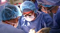 A doctor works with a surgical team in the operating room caring for a patient.