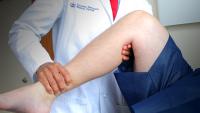 A physician performing a lower extremity physical examination.