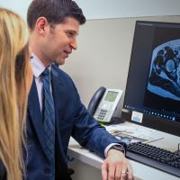 A doctor looking over an MRI on a computer